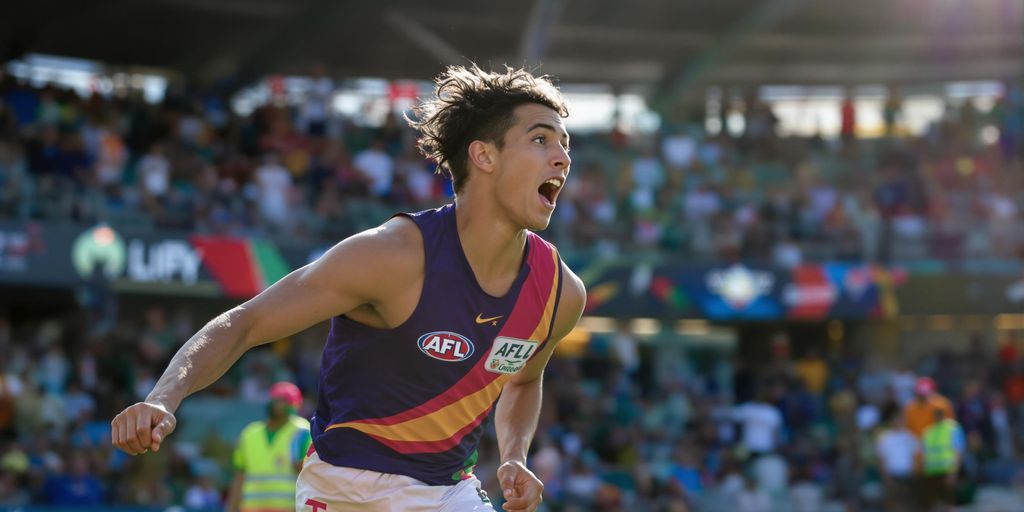 Young AFL player running on field during live match