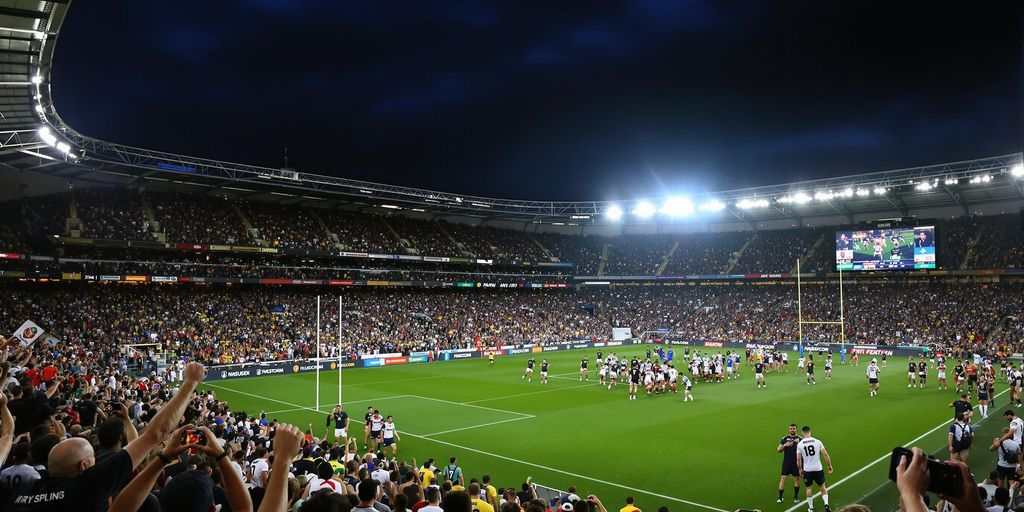 Rugby league players competing in a packed stadium at night.