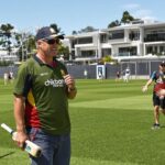 Australian cricket coach training young players on sunny field