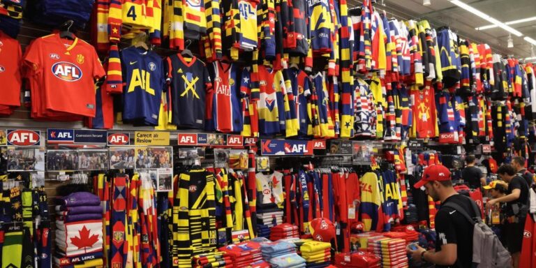 Aussie shoppers browsing colourful AFL team clothing in Kmart.