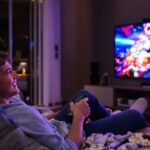 Person watching TV happily with popcorn in living room