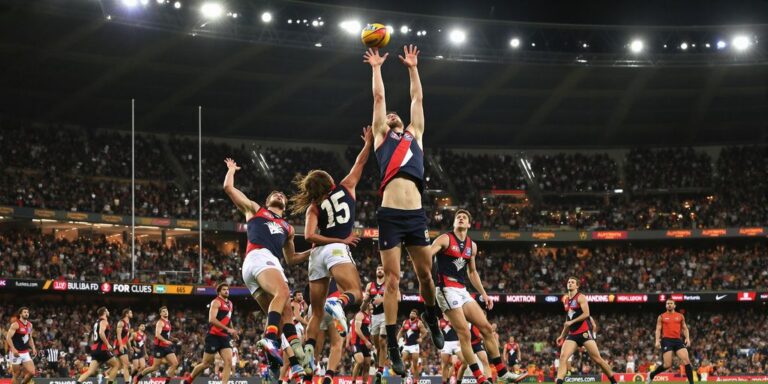 AFL players leaping for the ball in a packed stadium