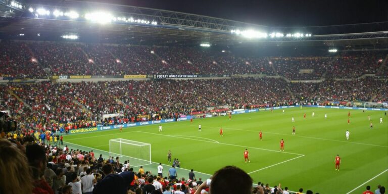 Football stadium packed with fans during night qualifiers match.