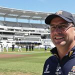 Australian cricket coach watching team train on sunny field