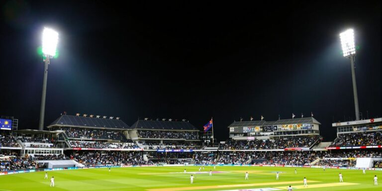 Cricket match at night in Australian stadium packed with fans.