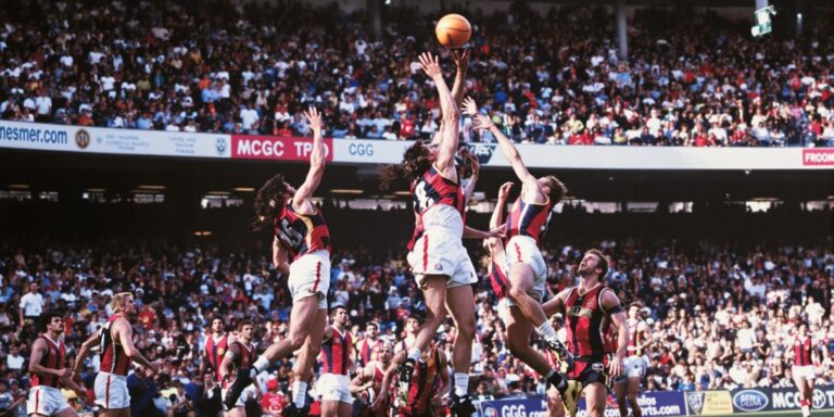 1984 AFL grand final players leaping for football
