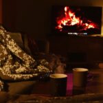 Cosy living room with sofa, blankets, remote and glowing TV